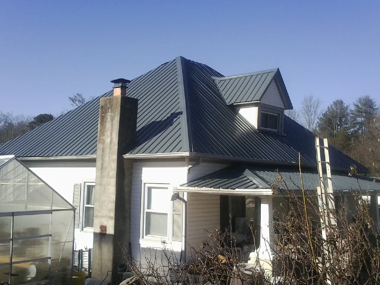 Dark blue standing seam metal roof on a white farmhouse with dormer — Slate & Tile Roof Repair by Roofing Brothers in Chatsworth