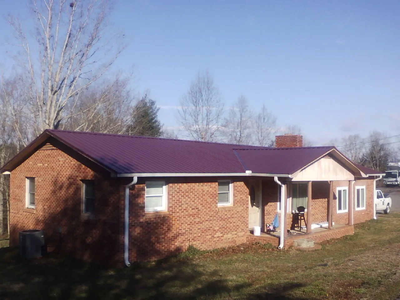 Burgundy metal roof on a brick ranch home with a new addition in Chatsworth