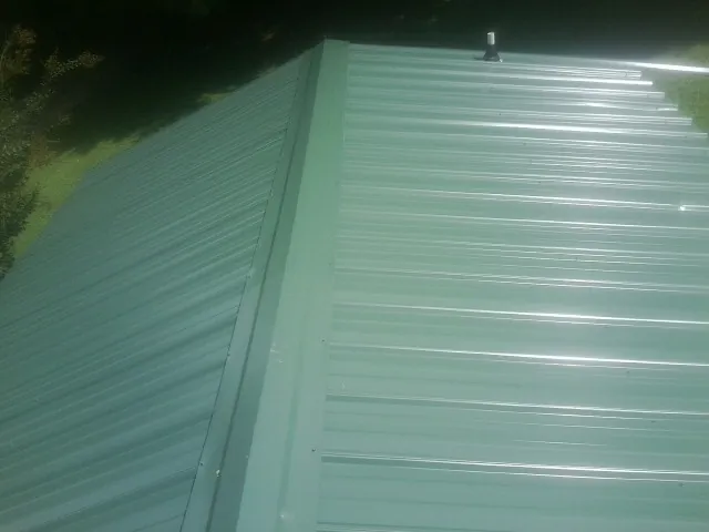 New green metal panels meeting at the ridge of a roof — Flat Roof Repair work by our crew in Chatsworth