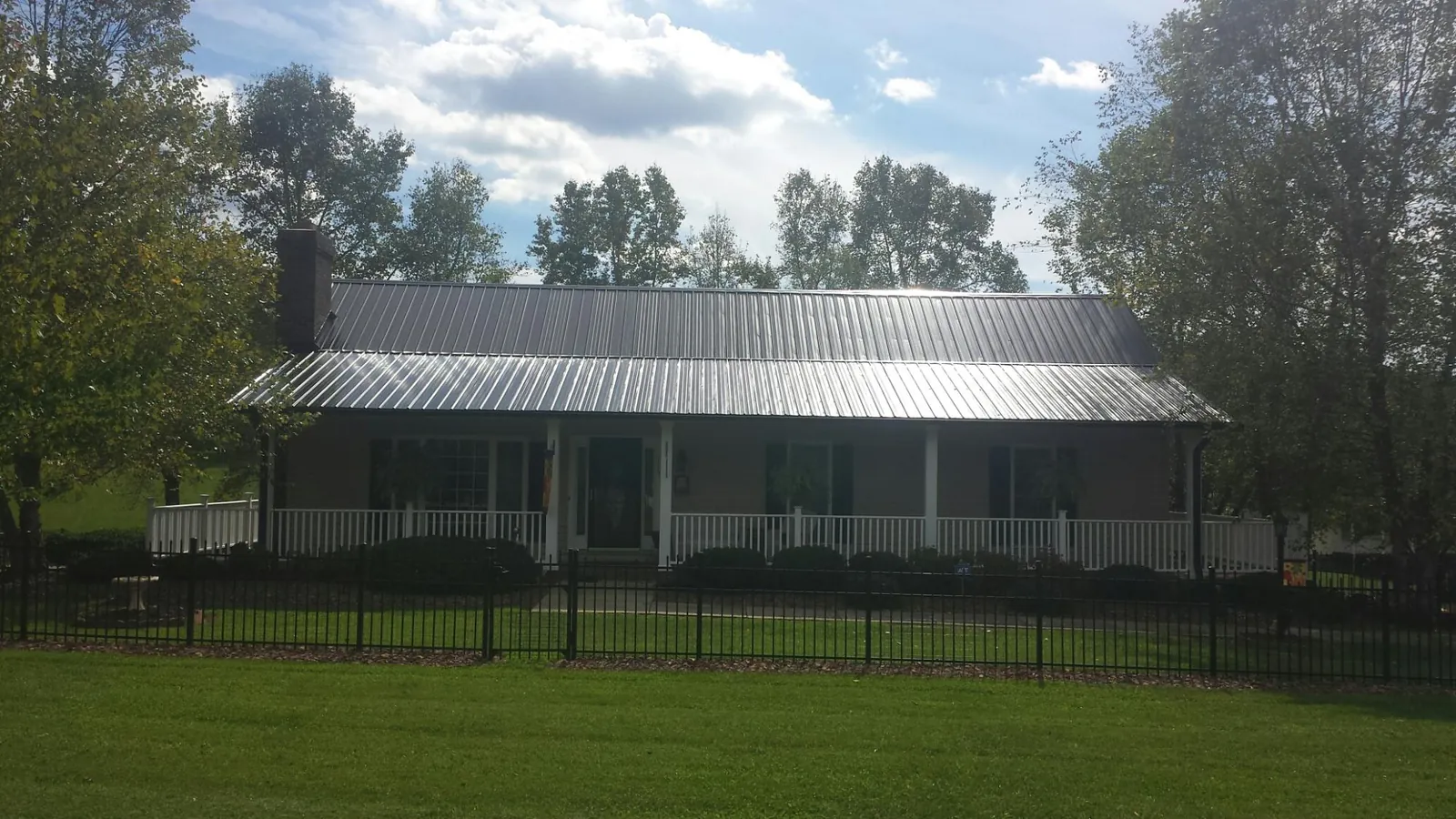 Gray metal roof on a brick ranch with a full width front porch — Gutter Guard Installation work by our crew in Chatsworth